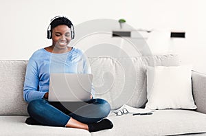 Smiling black woman working on computer, wearing headset