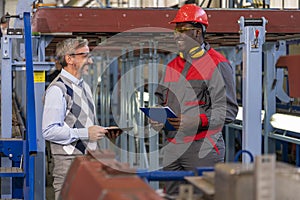 Smiling Black Worker in Protective Workwear And Smiling Caucasian Production Manager Having A Relaxed Chat