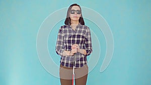 Smiling blind or visually impaired young woman with glasses and a cane