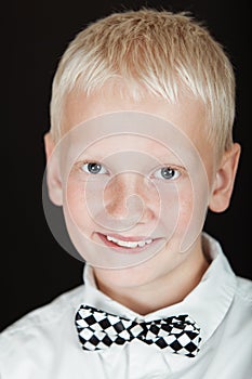 Smiling blond boy wearing checkered bow tie