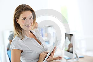 Smiling blond businesswoman using tablet at office