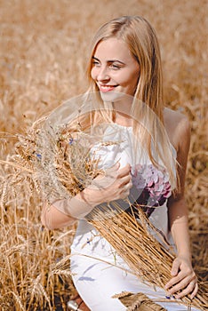 Smiling blond lady with sheaf of wheat sticks