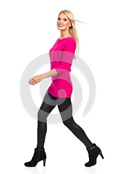 Smiling Blond Woman Is Walking And Looking At Camera. Side View. Isolated On White