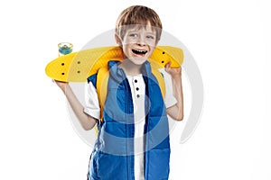 Smiling blonde boy holding yellow longboard and looking away on white background.