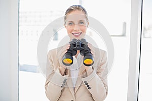 Smiling blonde businesswoman holding binoculars