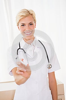 Smiling blonde doctor with syringe and stethoscope
