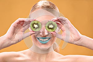 Smiling blonde female posing with kiwi fruit
