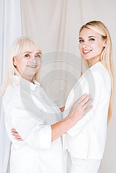 Smiling blonde grandmother and granddaughter embracing