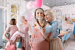 Smiling blonde-haired sister hugging her anticipating girl