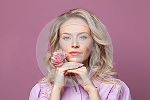 Smiling blonde mature woman face on bright pink background portrait