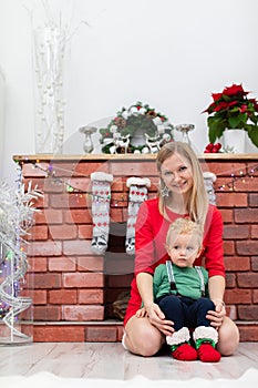 Smiling blonde in a red dress poses for a photo by the fireplace