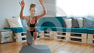 Smiling blonde in sports clothes exercising home sitting on floor indoors