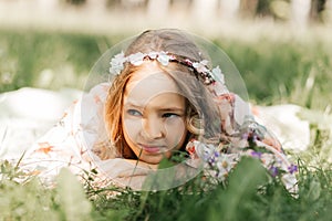 Smiling blonde teen girl posing in summer garden. Wearing flower wreath outdoors