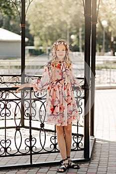 Smiling blonde teen girl posing in summer garden. Wearing flower wreath outdoors