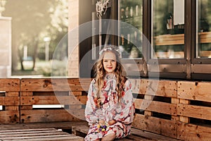 Smiling blonde teen girl posing in summer garden. Wearing flower wreath outdoors