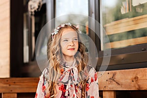 Smiling blonde teen girl posing in summer garden. Wearing flower wreath outdoors