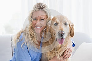 Smiling blonde woman hugging her golden retriever