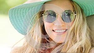 Smiling blonde woman wearing sunglasses and blue straw hat, laughing portrait, leisure and summer holiday concept