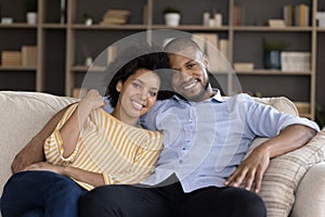 Smiling bonding mixed race couple resting on couch.