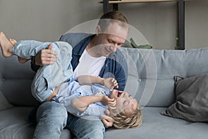 Smiling 35s young father tickling laughing cute little kid son.