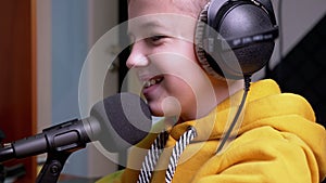 Smiling Boy-Blogger in Headphones, Talking into Microphone Leads Video Blog