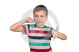 Smiling boy brushes his teeth and shows a thumbs up, isolated on a white background
