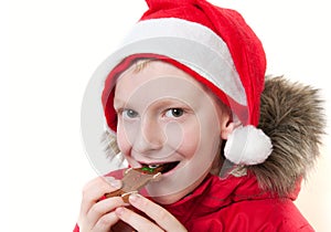 Smiling boy eating gingerbread man.