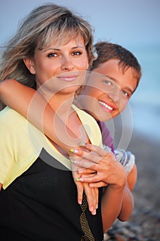 Smiling boy embraces young woman on beach