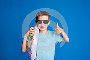 smiling boy enjoy summer resort with thumb up wearing blue T-shirt on light blue studio background