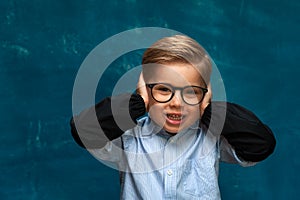 Smiling boy with eyeglasses on blue backdrop