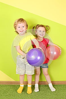 Smiling boy and girl with bright balls near the