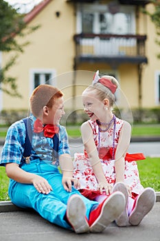 Smiling boy and girl in bright dancing suits sit photo