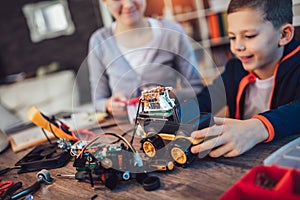 Smiling boy and girl constructs technical toy and make robot. Technical toy on table full of details