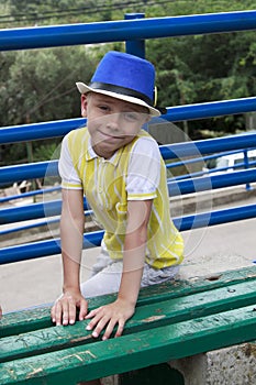 smiling boy in hat sitting on a bench