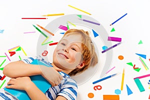 Smiling boy having a rest among heap of stationery photo