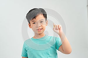 Smiling boy holding a capsule of vitamin on a white background