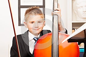 Smiling boy holding fiddlestick, play violoncello