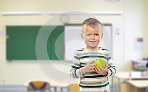 Smiling boy holding green apple at school