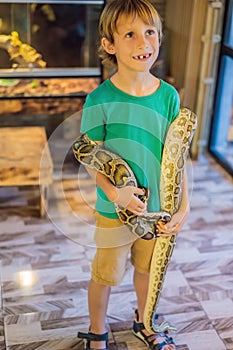 Smiling boy holding python in his hands