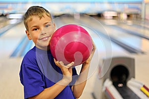 Smiling boy holds ball in bowling club