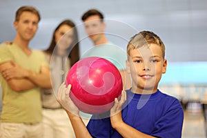 Smiling boy holds ball in bowling club