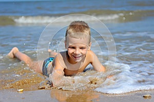 Smiling boy lying in water at the beach