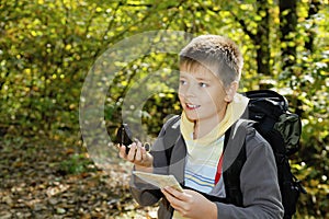 Smiling boy orienteering in forest