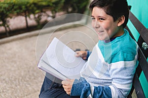 Smiling boy in the park holding a book