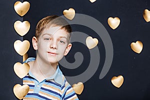 Smiling boy peeking on golden hearts background