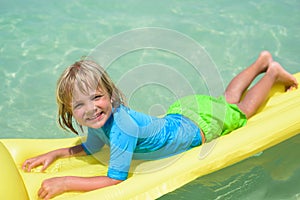 Smiling boy playing on the beach with air mattress