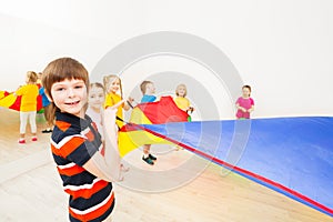 Smiling boy playing parachute with friends in gym