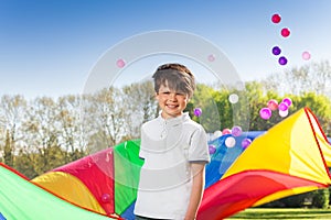 Smiling boy playing rainbow parachute in the park