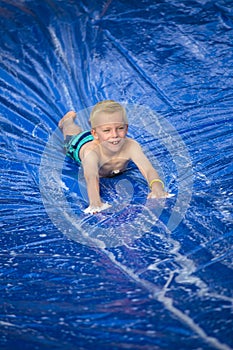 Smiling boy playing on a slip and slide outdoors