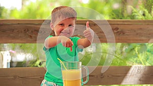 Smiling boy pointing finger at orange juice